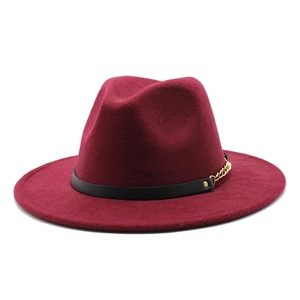 Detail of burgundy wool fedora hat featuring a black leather band and gold chain accent