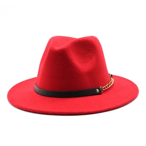 Detail view of a red wool fedora hat featuring a black leather band and gold chain accent