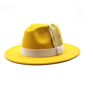 Detail of yellow wool fedora hat with white ribbon band and golden feather accessory