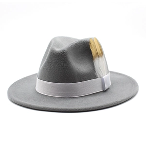 Détail d'un chapeau fedora en laine gris foncé avec ruban blanc et plume dorée