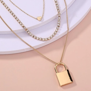 Detailed macro view of triple-layered gold necklace with heart and lock pendants