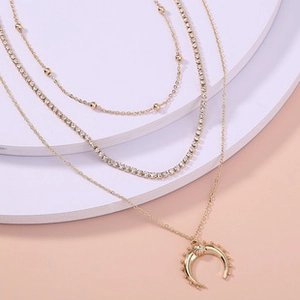 Close-up of golden multi-layer necklace with rhinestones and a crescent moon pendant