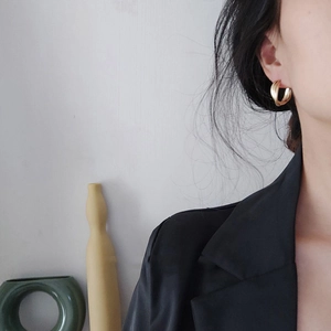 Close-up of matte gold double-layered C-shaped earrings on a model in a minimalist style