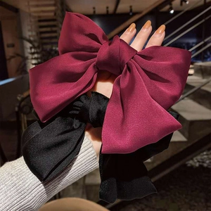 Solid wine red and black satin bow hair clips shown in hand with elegant silk finish