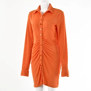 Detail of orange long sleeve shirt dress showing front button pleated texture