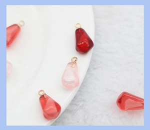 Macro view of crystal resin pomegranate seed charms with golden metal loops