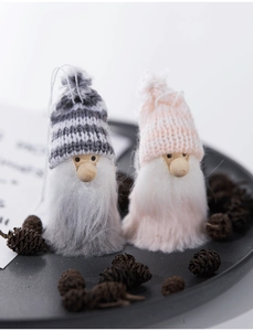 Detail of grey and pink knitted Christmas gnomes with long plush beards on a tray
