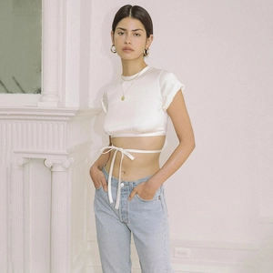 Detail of white crop top featuring short sleeves and stylish waist tie-up design