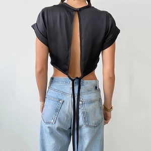 Detailed back view of a black satin crop top featuring an open back with lace-up ribbon tie