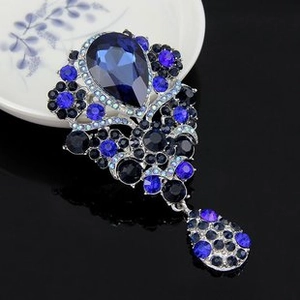 Detailed shot of vintage enamel flower brooch with blue and black gemstones
