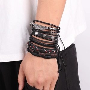 Close-up of men's layered leather bracelet set featuring silver feather and star charms