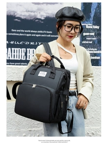 Modern black nylon diaper backpack with 'YOU ARE MY SUNSHINE' label worn by a model
