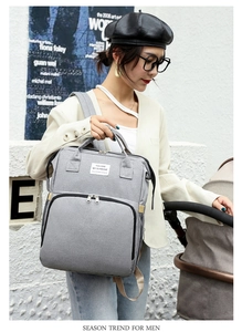 Detail of grey multifunctional diaper bag backpack with woven label and side zipper pocket