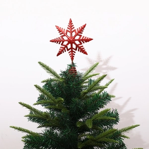 Red glitter snowflake tree topper on a green Christmas tree with a sparkling finish
