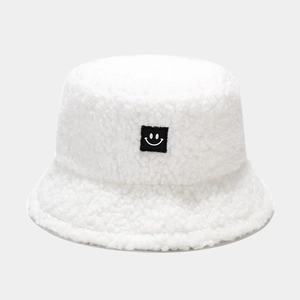 Close-up of white teddy fleece bucket hat texture with minimalist smiley face patch