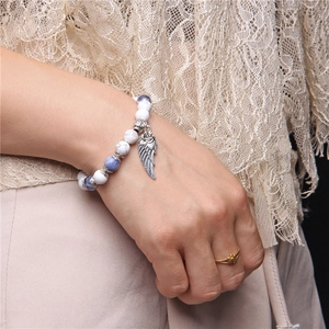 Detail of natural stone beaded bracelet with white turquoise and silver angel wing charm