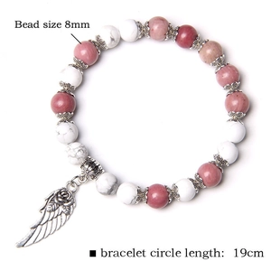 Detail of 8mm bead bracelet with natural stone texture and silver wing charm pendant