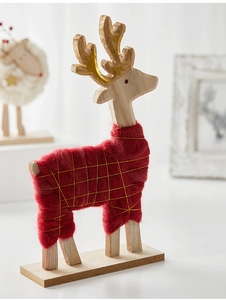 Detail of Nordic wooden reindeer decor with red wool and gold accents on a desk