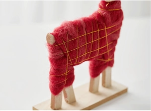 Detail of red wool Christmas ornament with gold mesh patterns on light wooden base
