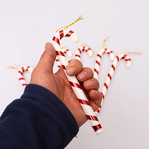 Set of six red and white striped Christmas candy cane ornaments held in hand decoration