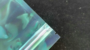 Detailopname van de holografische hersluitbare zak met regenboogfolie en de druksluiting