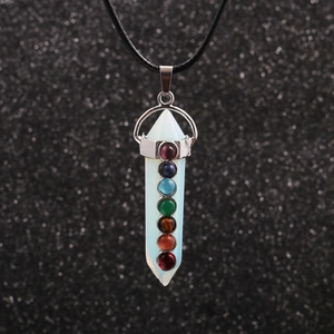 Macro detail of hexagonal white crystal pillar pendant with seven chakra beads on black rope