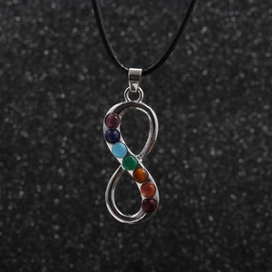 Detail of silver infinity chakra pendant with seven colorful gems on a black cord