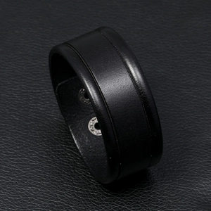 Close-up of black leather bracelet featuring metallic snap buttons and premium texture
