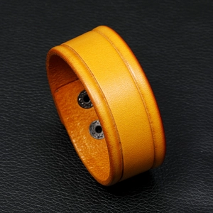 Macro shot of yellow leather wide bracelet with two metal snap buttons for adjustment