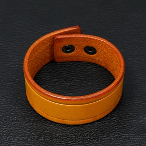 Detail of vintage brown leather bracelet featuring adjustable double-snap button closure
