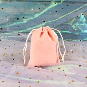 Macro detail of a soft pink velvet jewelry pouch with white braided drawstring