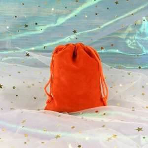 Detailed close-up of an orange velvet drawstring pouch with soft texture and golden stars