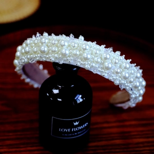 Detailed macro shot of a white baroque pearl headband on a dark decorative glass bottle