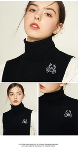 Close-up of crab-shaped brooch with blue stone on a black sweater, showing fine details