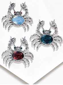 Detailed view of crab brooches in light blue, dark blue, and red with rhinestone crystals