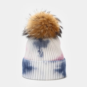 Primer plano detallado del gorro de punto tie-dye con un pompón de piel marrón