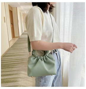 Detail of light green pleated cloud bag featuring metal protective feet and slim strap