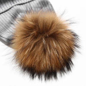 Macro view of fluffy gradient brown fur pom-pom on a striped grey knit beanie hat