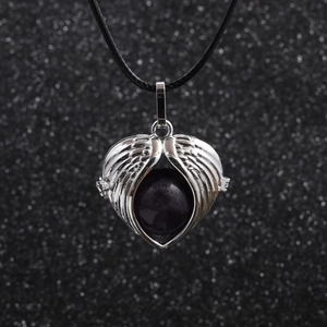 Angel wings necklace with purple gemstone pendant on black cord shown on dark background
