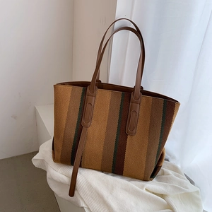 Gros plan d'un sac cabas tissé à rayures marron avec fines bandoulières en cuir PU