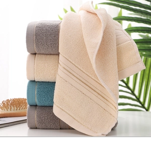 Stack of thick absorbent cotton towels in gray and beige with elegant striped borders