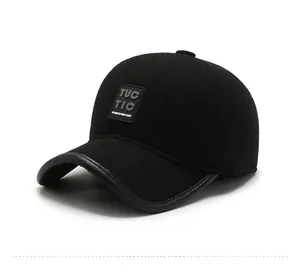 Detail of black wool baseball cap with TUC TIC badge and leather brim piping finish