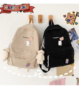 Detail of cute Japanese-style backpacks in beige and black with plush bear charms