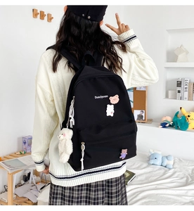 Detail of cute black canvas backpack with bear charms and logo in a cozy bedroom