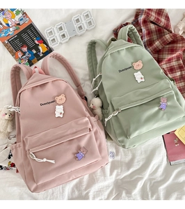 Detail of pink and green school backpacks with cute bear patches and Duociyuan brand logo