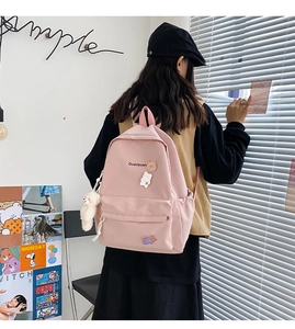 Pink canvas backpack with cute animal pins and white plush charm on side detail