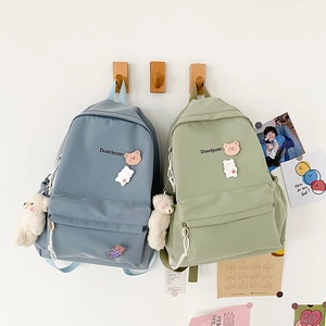 Detail of blue and green nylon backpacks with cute bear pendants and cartoon pins
