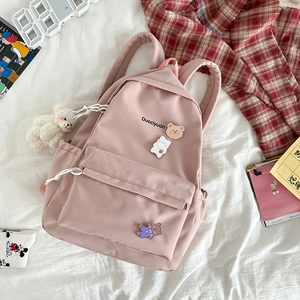 Pink canvas backpack with cute bear accessories and pocket detail on white background