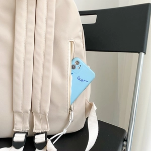 Detail view of off-white nylon backpack featuring side zipper pocket and adjustable strap