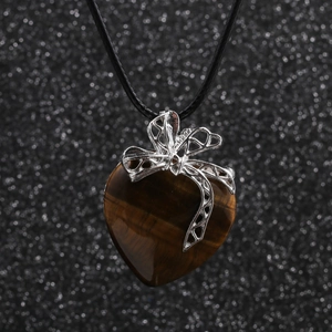 Collier en cordon avec pendentif cœur en oeil de tigre et nœud argenté sur fond noir